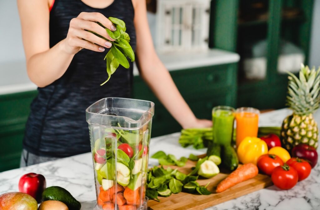 A person putting fruits and vegetables into a blender to make an eye healthy smoothie.