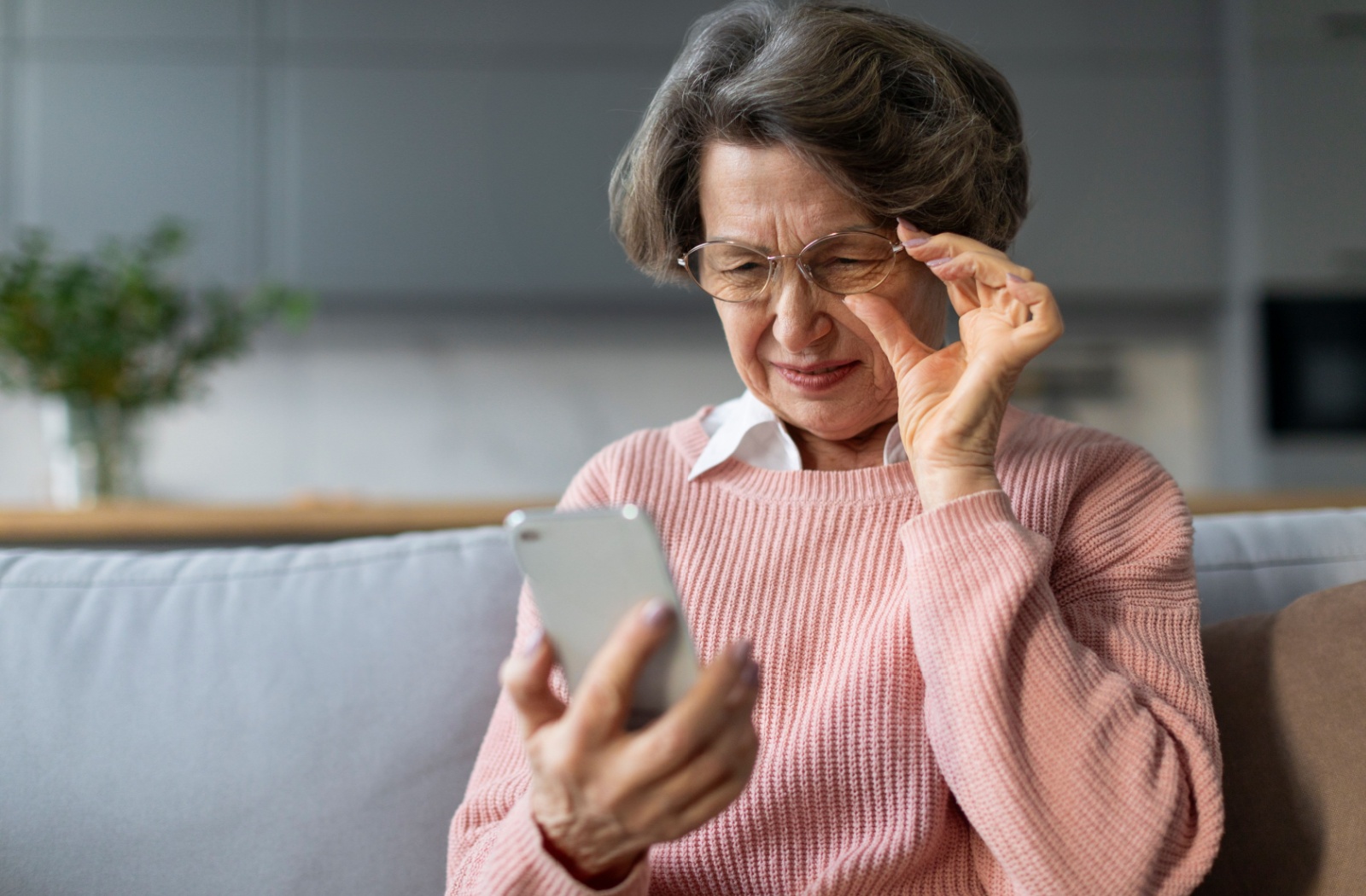 a person squinting to see their phone due to their cataracts symptoms