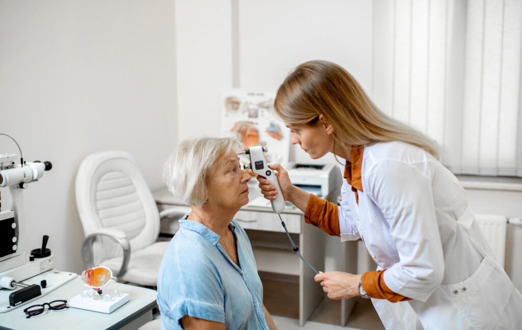 An optometrist checks their senior patient's eye pressure to monitor for eye conditions like glaucoma.