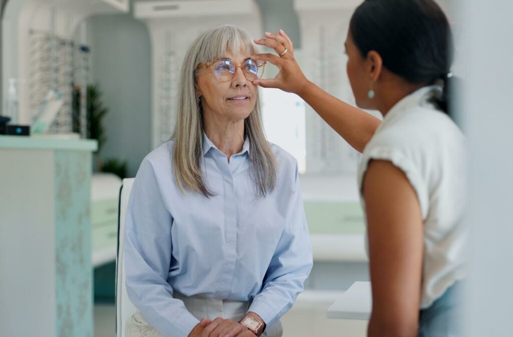 A patient at their local optometrist's office having their eyeglasses adjusted by an optician.