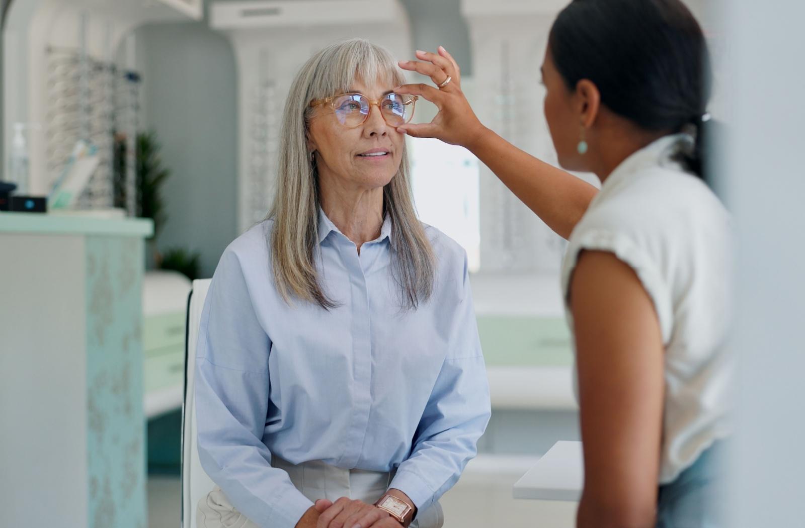 A patient at their local optometrist's office having their eyeglasses adjusted by an optician.