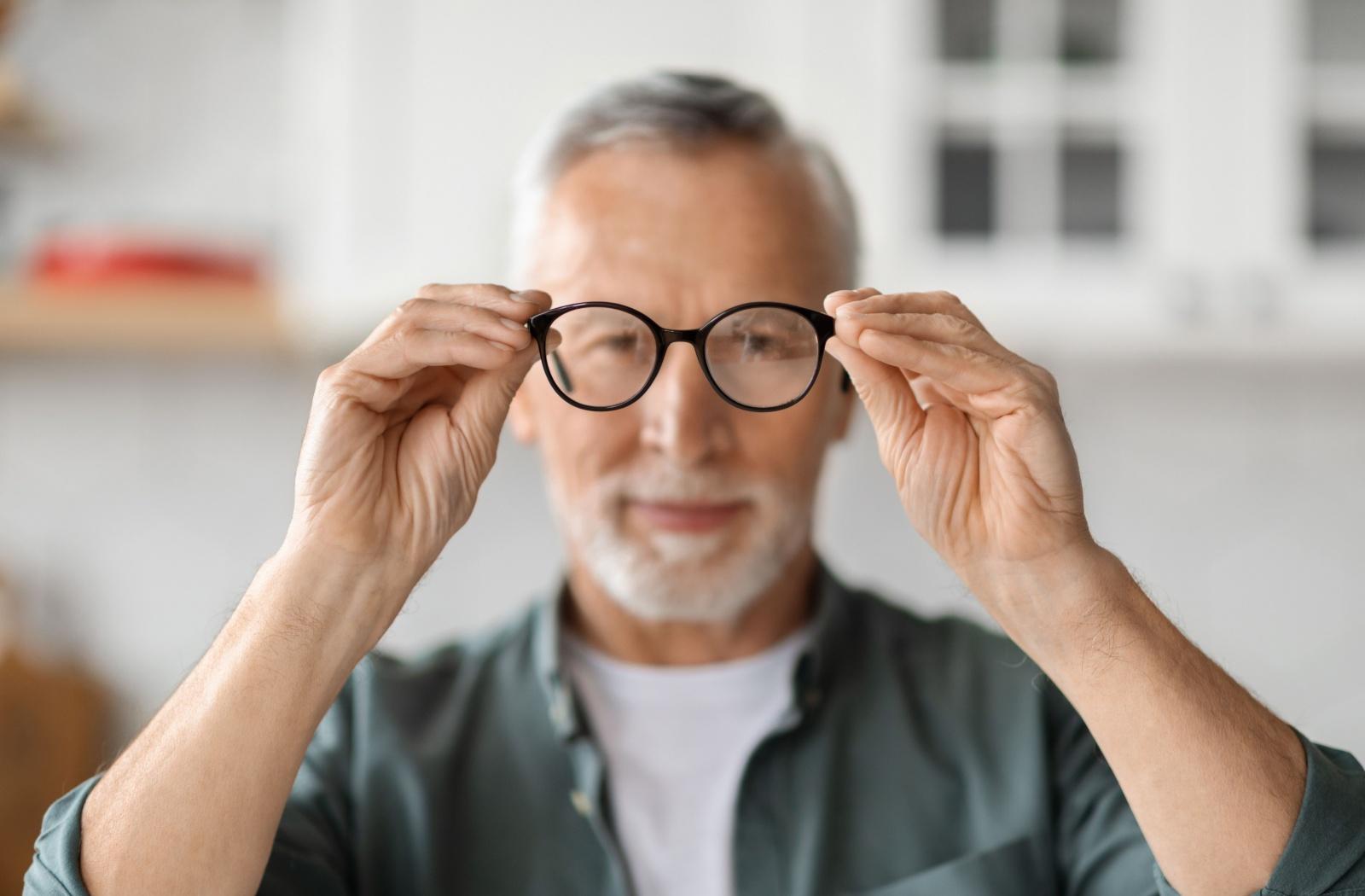 A person holding a pair of eyeglasses out in front of their face.